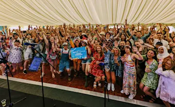 Hundreds of Explore Learning staff at a celebration event smiling at the camera