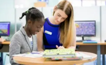 Tutor helping a child read in Explore centre