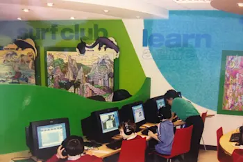Picture of the 1st centre with children using computers and a tutor helping them