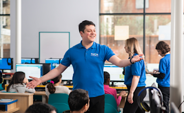 An Explore Learning tutor stands in the middle of a busy learning centre.