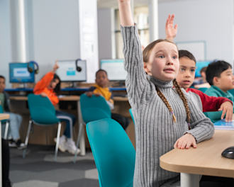 Girl raising her hand to answer a question in an Explore Learning tuition centre