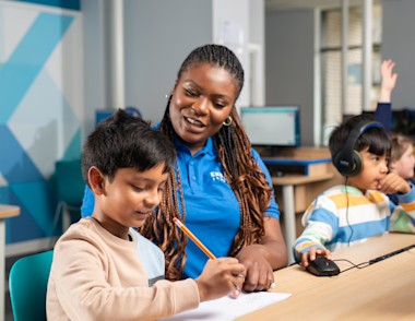 An Explore Learning tutor works with a child at a desk.